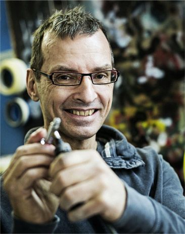 Stephan Beutler lächelt in die Kamera und hält eine Lackierpistole in der Hand.